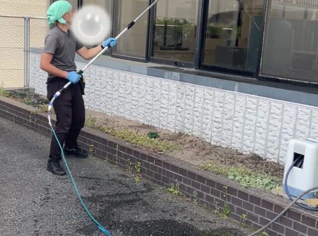 水道局佐伯営業所の屋外窓ガラスをブラシと水で清掃するスタッフ