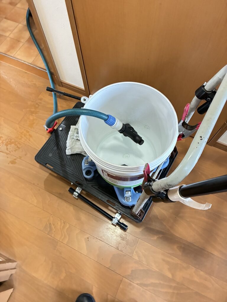 古いワックスを落とす液を撒くため、台車のバケツとホースを組み合わせた自作の道具