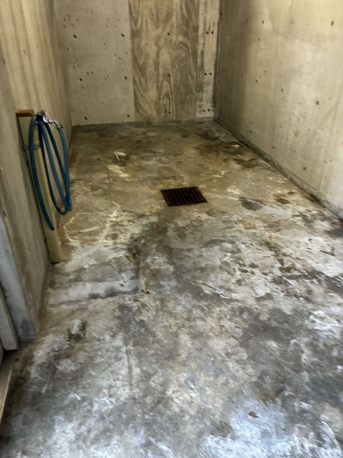 第3集積所の清掃前。排水口周辺の床面に黒ずみと白色の変色が見える